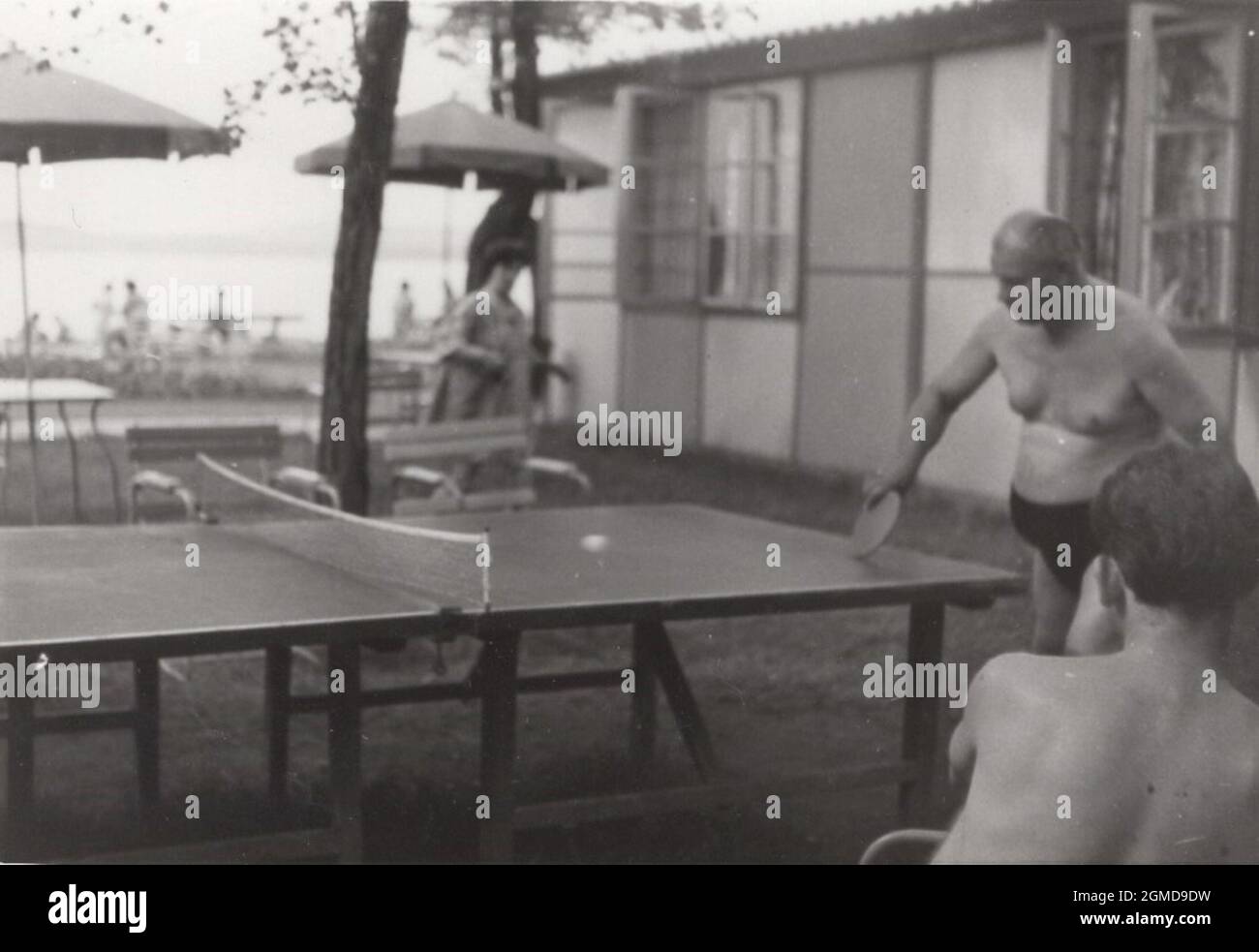 original retro photo about a seaside resort or any holiday place where an old gentleman is playing table tennis. He looks like very confident, profession, champion, world class player. from the 1960's. / vintage beach Stock Photo