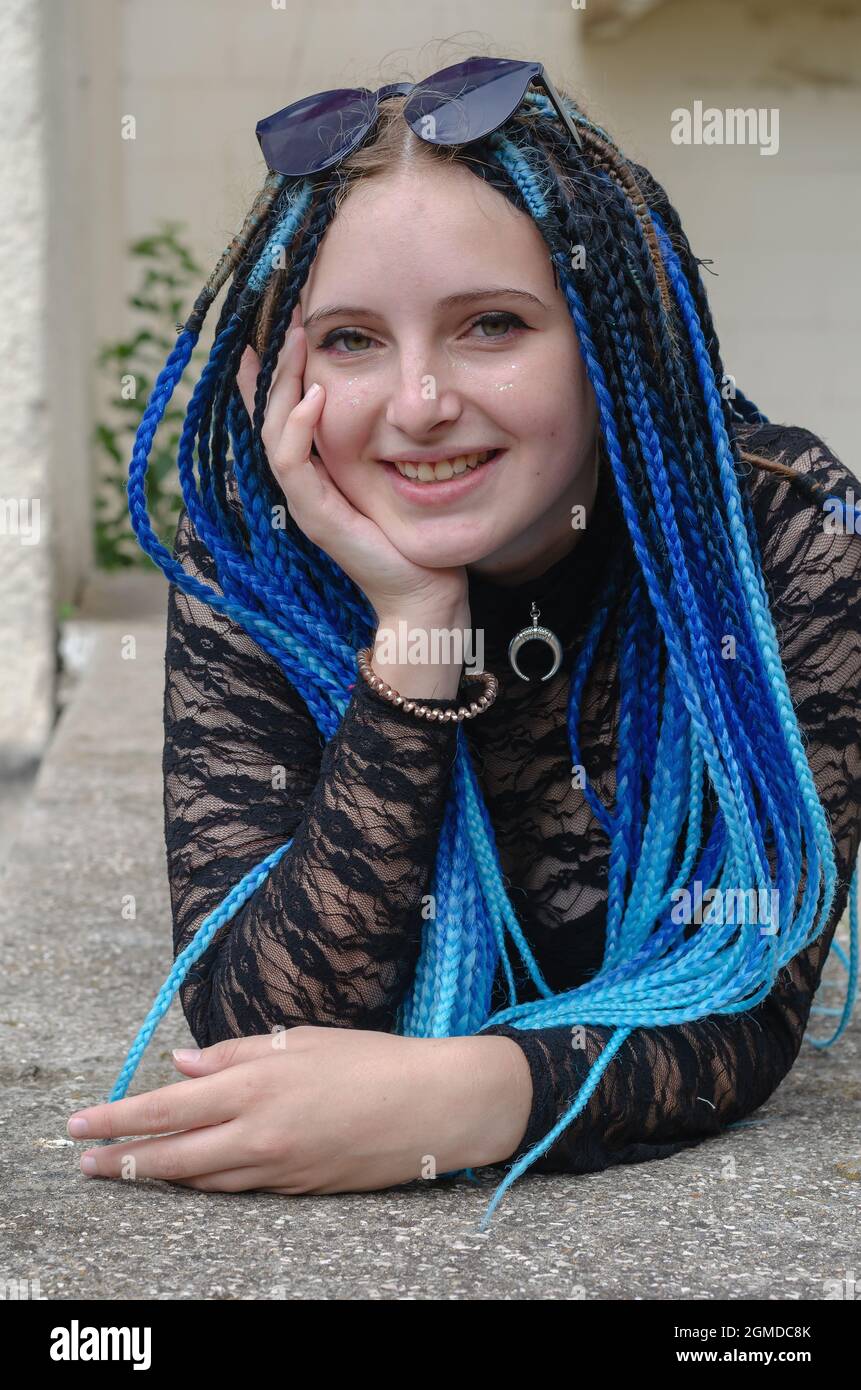 Portrait of a lovely young woman lying on a concrete pedestal. T Stock Photo