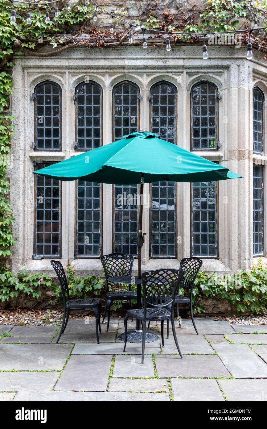Wrought iron patio set and turquiose umbrella create a lovely setting in formal garden Stock Photo