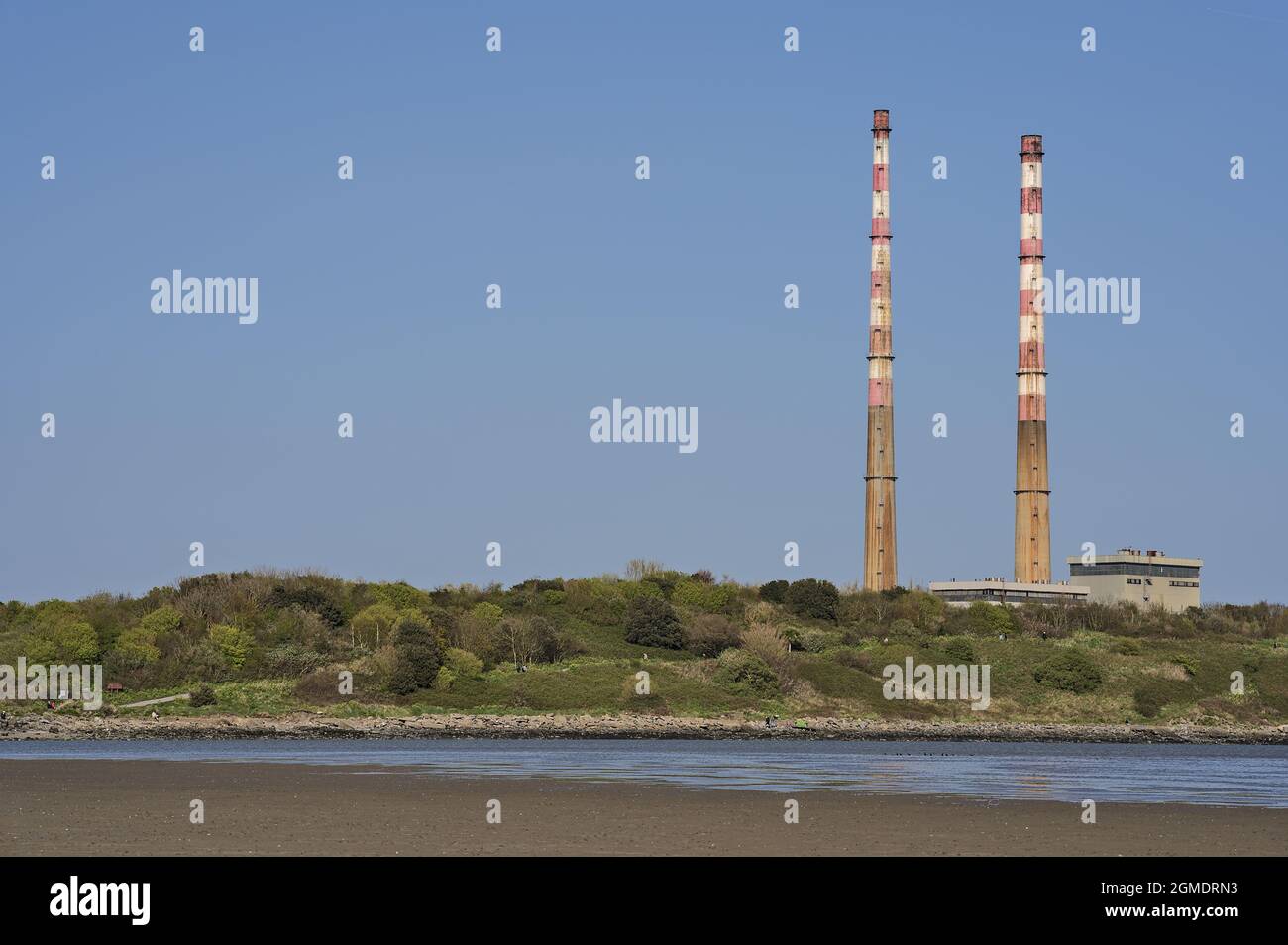 Beautiful closeup bright view of iconic Poolbeg CCGT station chimneys against clear blue sky seen from Sandymount Beach, Dublin, Ireland. Soft colors. Stock Photo