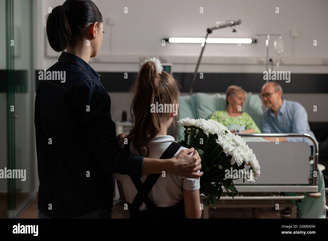 Caring granddaughter bringing flowers to sick elderly grandmother