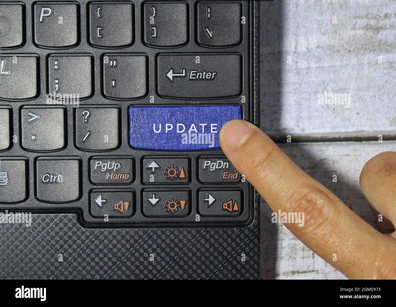 Finger pressing a blue key labeled UPDATE with symbol on a computer keyboard concept Stock Photo