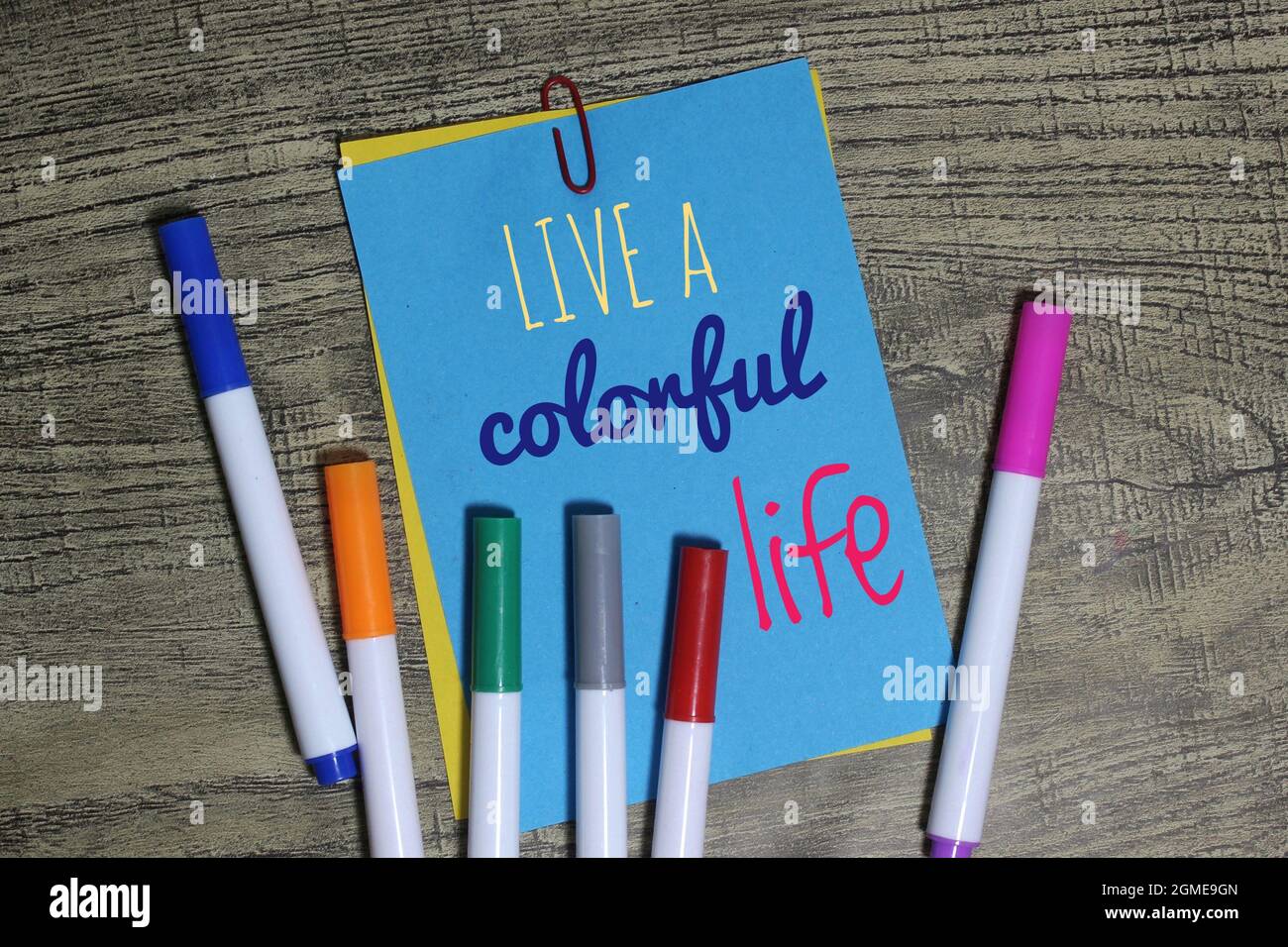 Motivational quotes about life. Top view of color pen and color paper with text LIVE A COLORFUL LIFE. Selective focus. Stock Photo