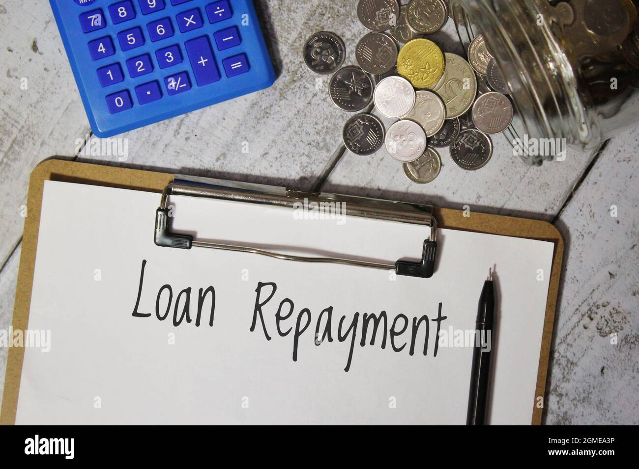 Top view of calculator, coins and paper with text LOAN REPAYMENT. Stock Photo