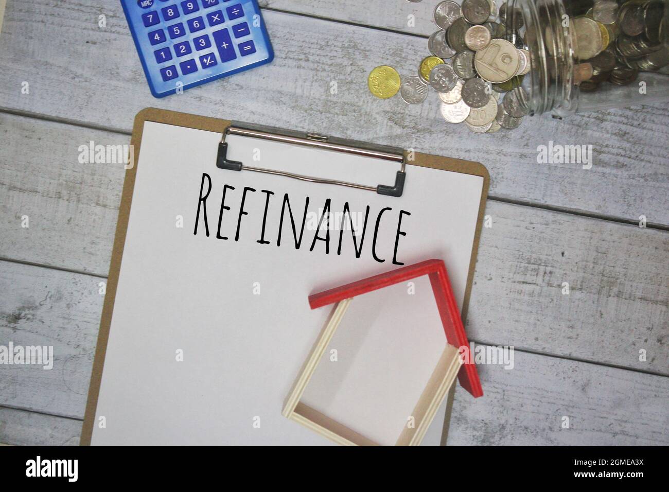 REFINANCE text, miniature house, calculator and coins on wooden table. Stock Photo