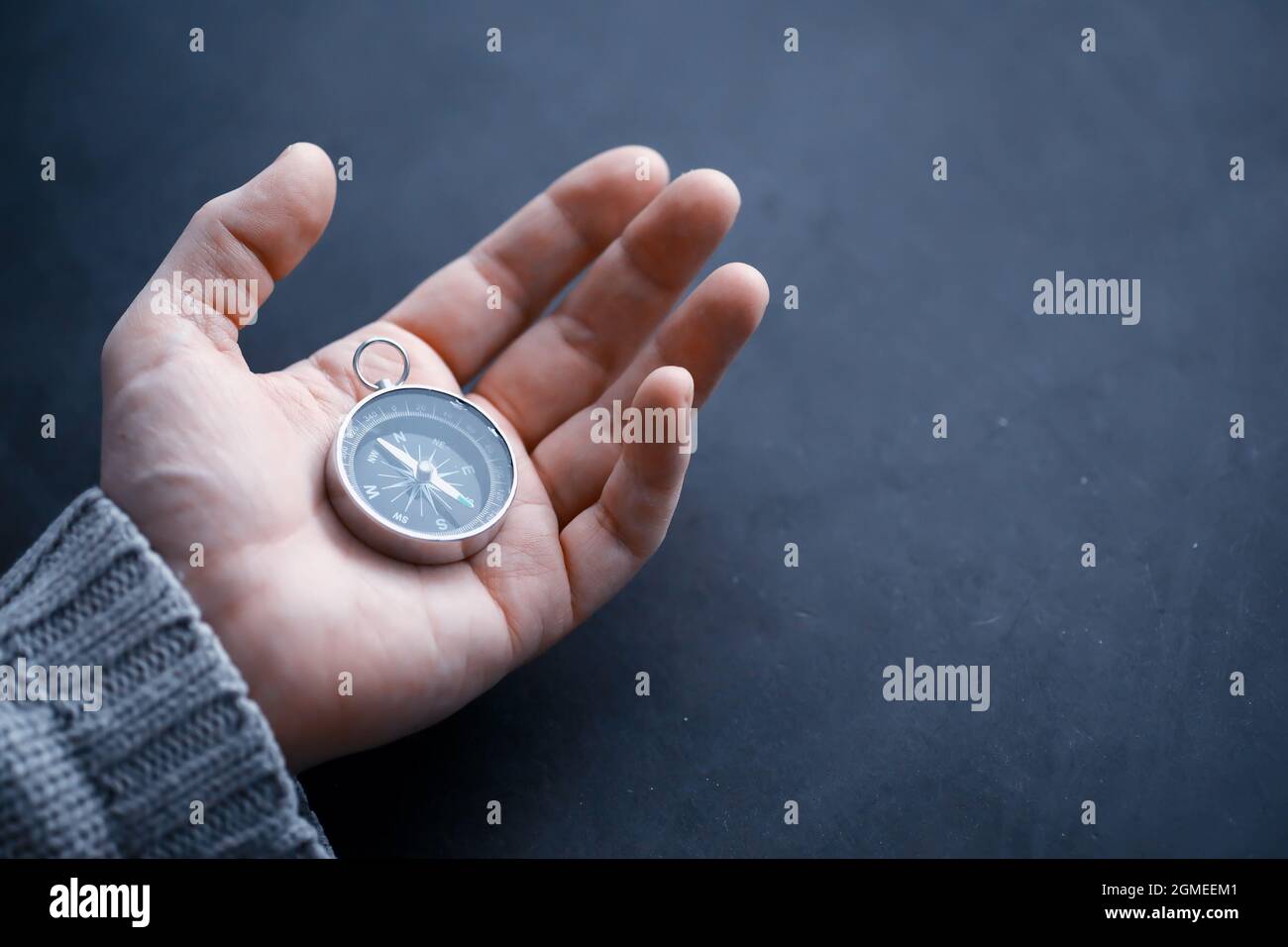 Travel concept. Magnetic compass in the hand. Retro navigator in hand map and airplane background. Adventure Background. Stock Photo
