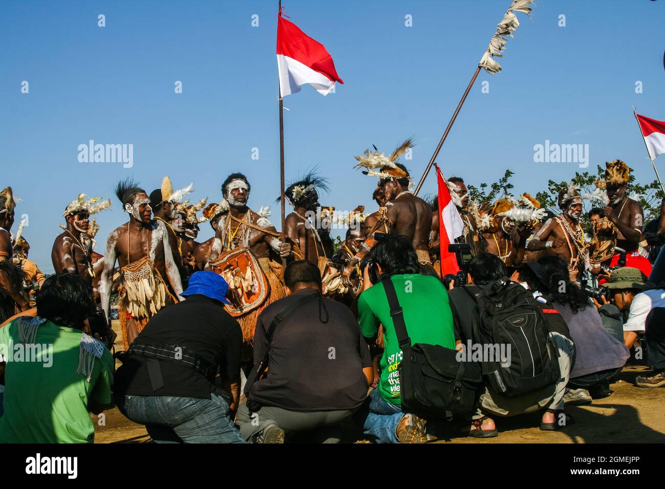 Photographers are taking pictures of a group of Asmat men dancing while carrying red and white flags at the Asmat Festival held in Ancol. Stock Photo