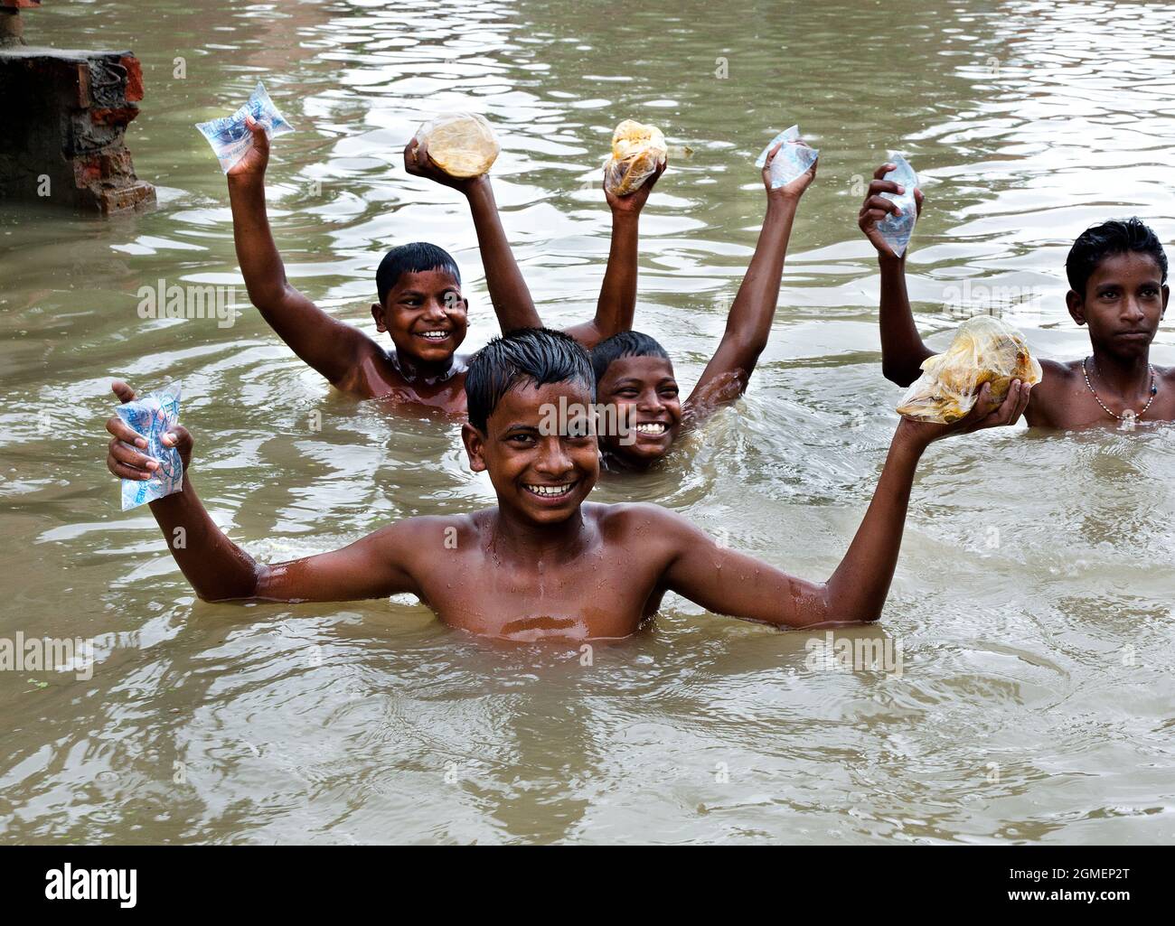 The rural village children of the flood area are very happy for taking relief i.e. food packet and pure water from rescure team at Varanasi in India. Stock Photo