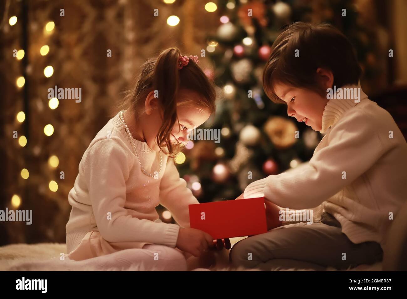 Family on Christmas eve at fireplace. Kids opening Xmas presents Christmas Eve Traditiona