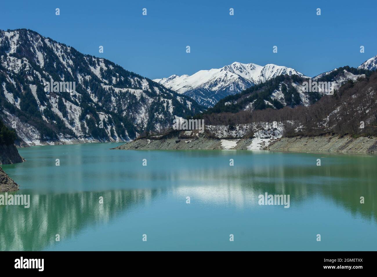 TOYAMA, JAPAN – APRIL 28, 2018: Landscape view of Kurobe dam in sunny day with clear blue sky at The Tateyama Alpine Route or Japan Alps snow wall. Pr Stock Photo