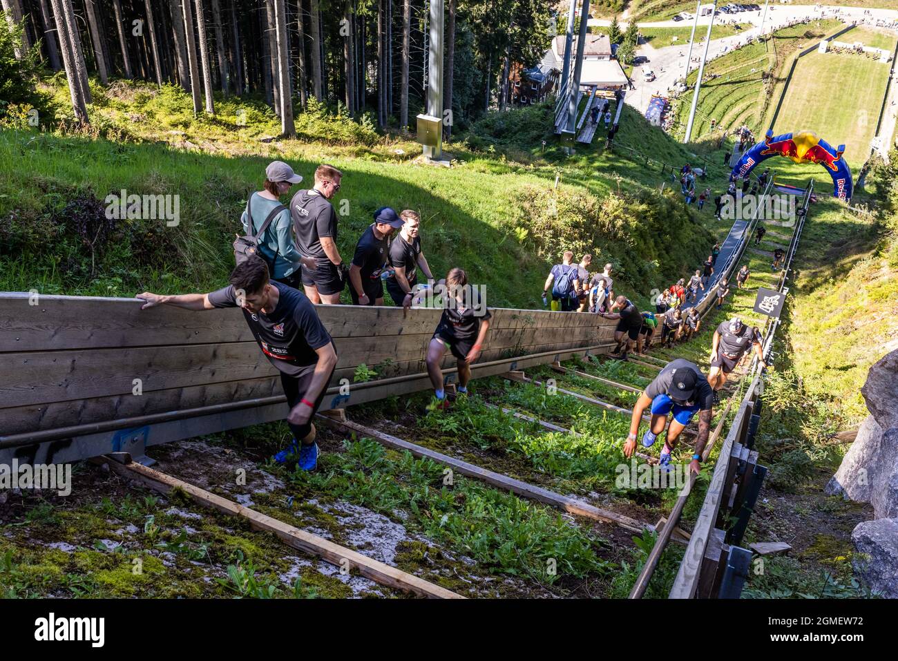 Titisee Neustadt, Germany. 18th Sep, 2021. Participants of the "Red Bull  400" ski jump run up the slope of the Hochfirstschanze while spectators  stand at the edge of the slope. More than