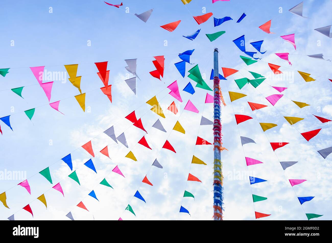 vivid color of Thai's style fancy party flag strips decoration on a fancy still pole with blue sky and white cloud in background Stock Photo
