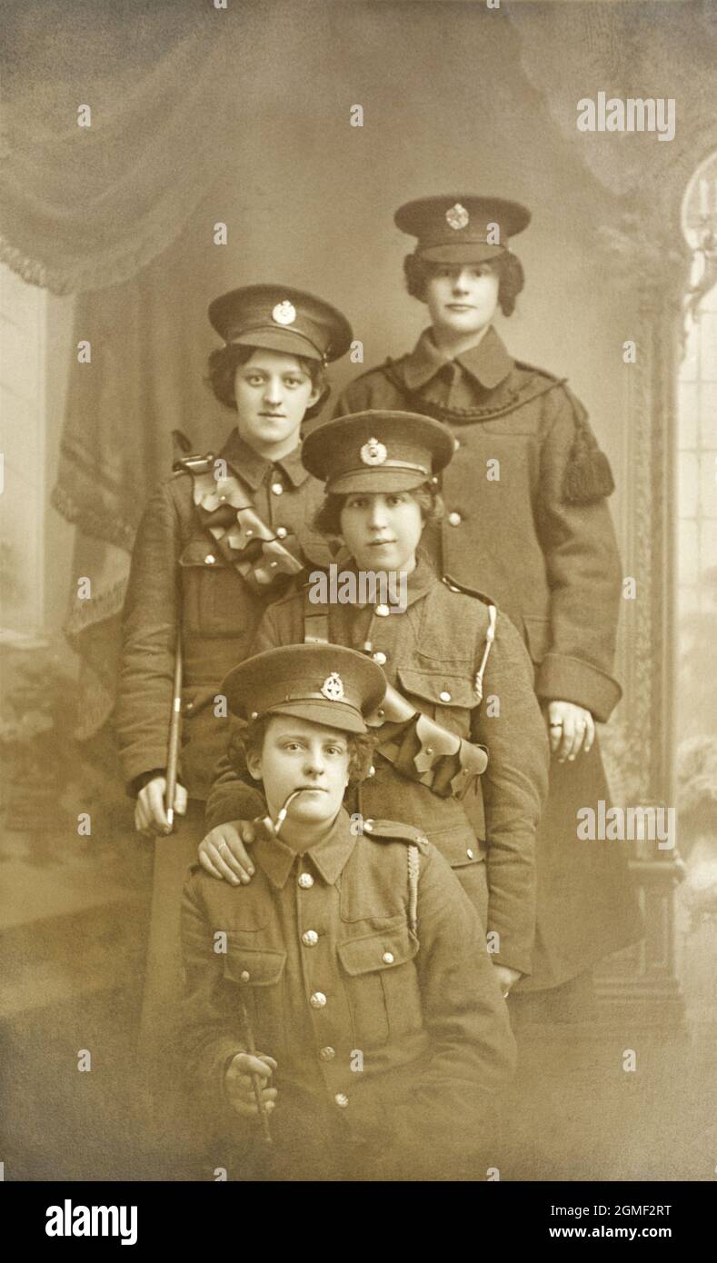 A portrait of four ladies in the uniforms of First World War British soldiers. The middle two are wearing the cap badge of the Royal Engineers, the lady at the font has a Victorian cap badge of the East Lancashire Regiment. The lady at the back seems to have accessorised her uniform with what looks to be a curtain tassle. Stock Photo