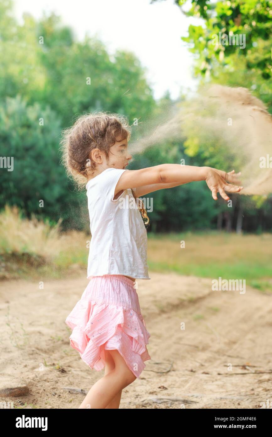 Cute Little girl play with sand in park on a summer day at sunset. Stock Photo