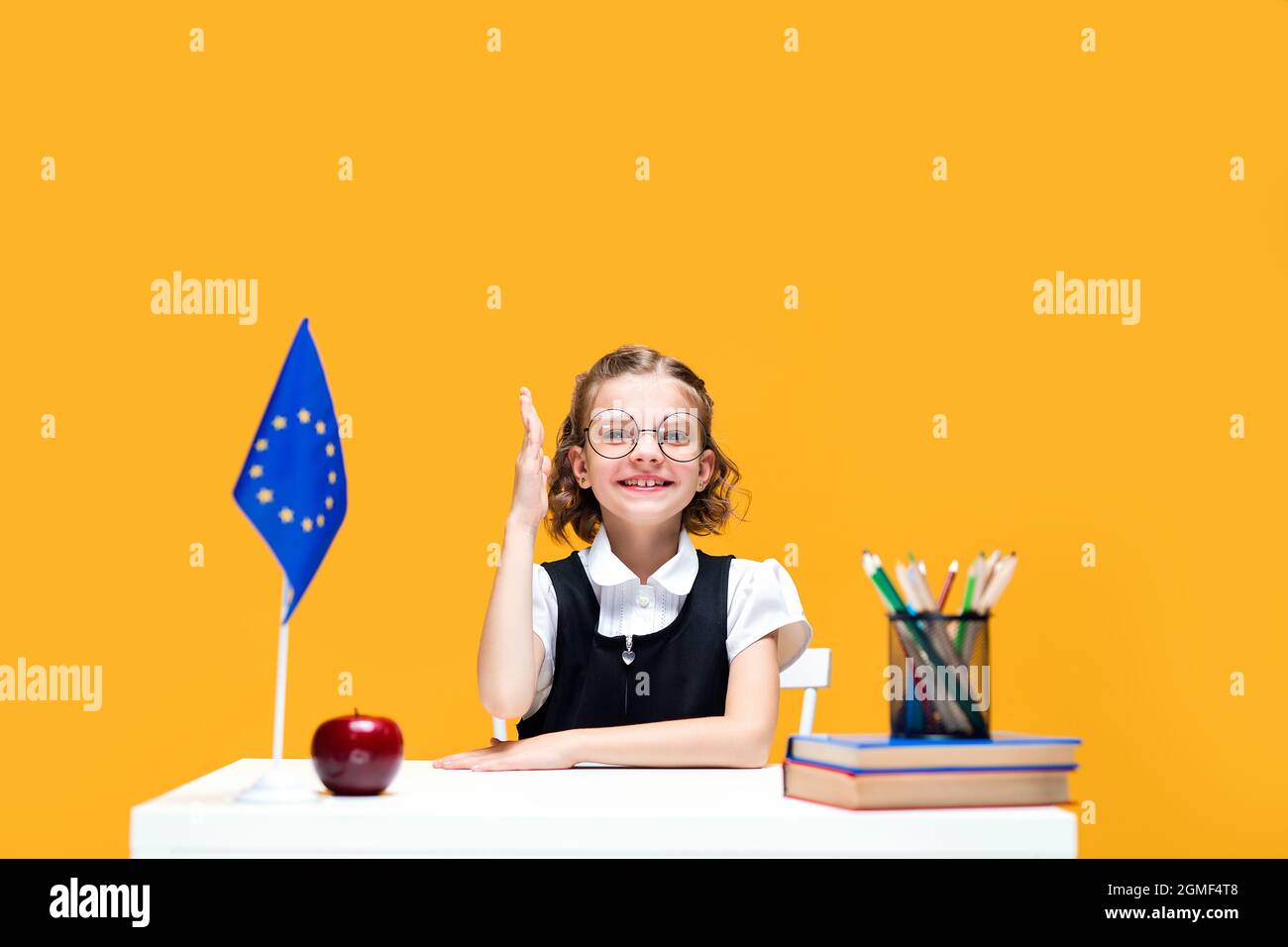 Caucasian schoolgirl raising hand sitting at the desk during lesson ...