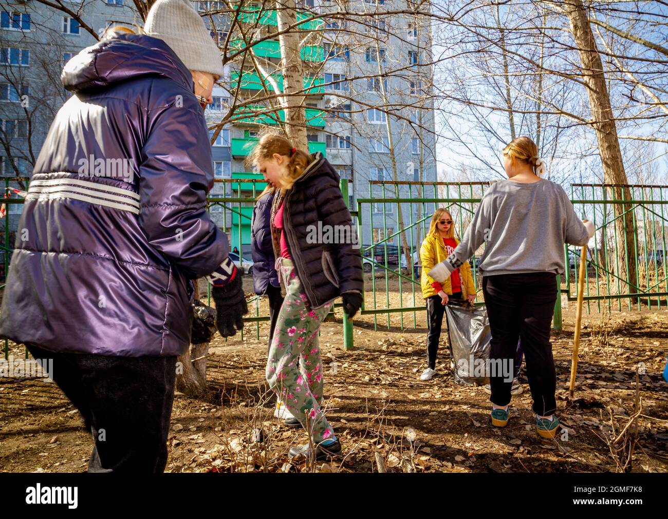 Omsk, Russia. 24 April, 2021. Four schoolgirls are actively cleaning the schoolyard. Traditional Russian events for the preparation of school territor Stock Photo
