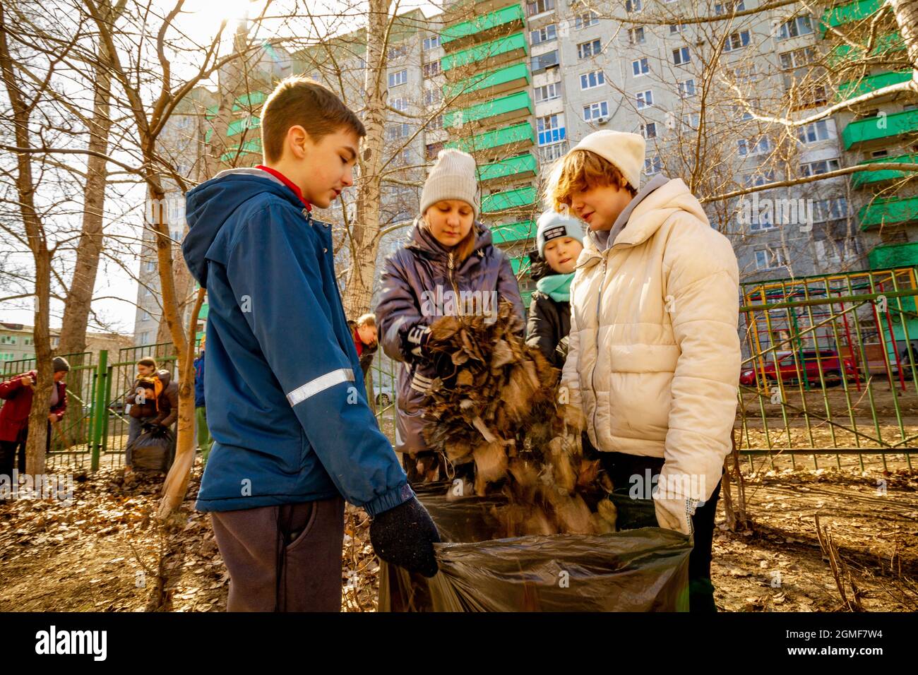 Omsk, Russia. 24 April, 2021. A schoolboy with three schoolgirls are packing a bag of foliage. Traditional Russian events for the preparation of schoo Stock Photo