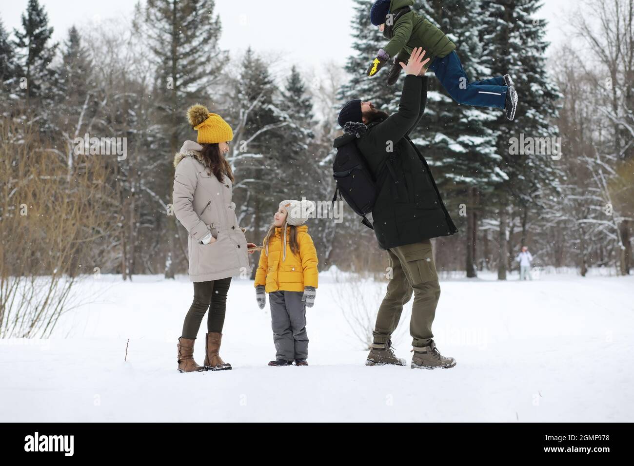 Happy family playing and laughing in winter outdoors in snow. City park ...