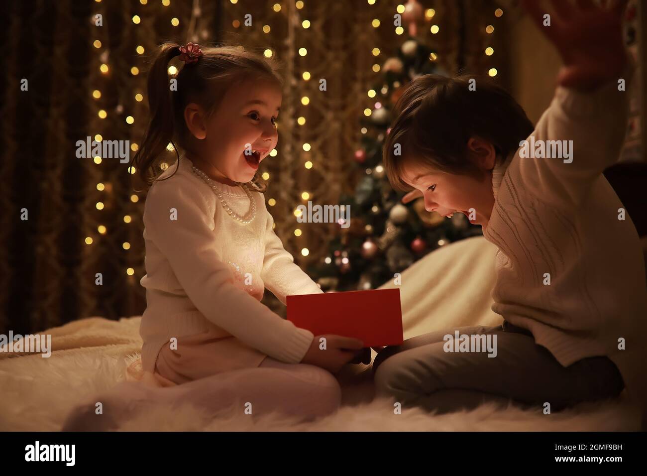 Family on Christmas eve at fireplace. Kids opening Xmas presents Christmas Eve Traditiona