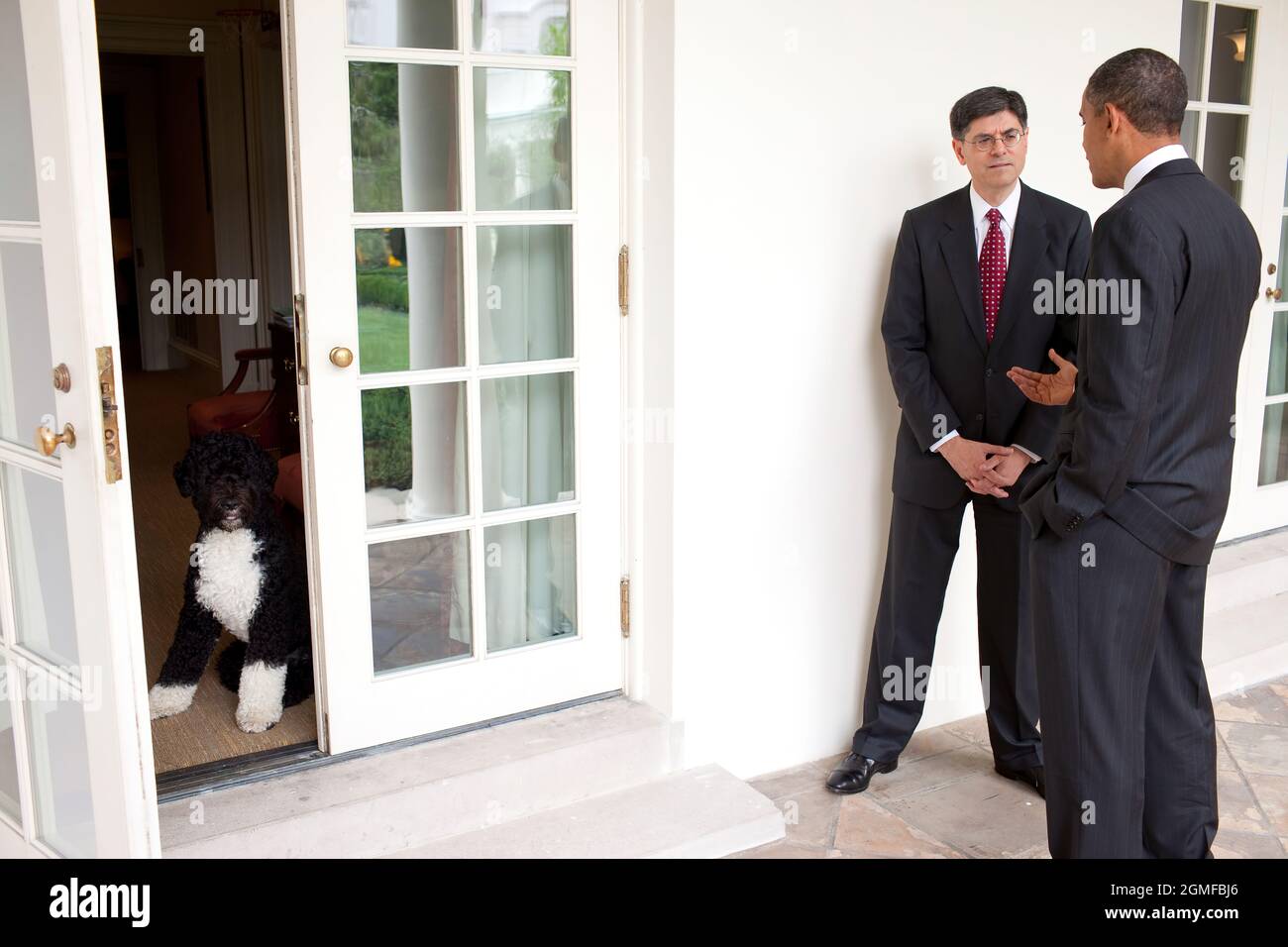President Barack Obama talks with Jack Lew on the Colonnade of the White House, after he announced Lew’s nomination to replace Peter Orszag as director of the Office of Management and Budget, July 13, 2010. At left, Bo, the Obama family dog, waits for the President inside the doorway of the Outer Oval Office. (Official White House Photo by Pete Souza) This official White House photograph is being made available only for publication by news organizations and/or for personal use printing by the subject(s) of the photograph. The photograph may not be manipulated in any way and may not be used in Stock Photo