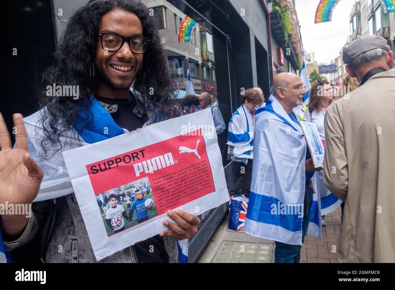 London, UK. 18 Sept 2021. A man holds a poster supporting Puma which says football brings Jews and Arabs together. Palestinian football clubs urge people to support the boycott of Puma and the #BoycottPUMA Global Day of Action. They call on Puma to end its sponsorship of the Israel Football Association, which governs teams in illegal Israeli settlements in the occupied Palestinian West Bank Peter Marshall/Alamy Live News Stock Photo