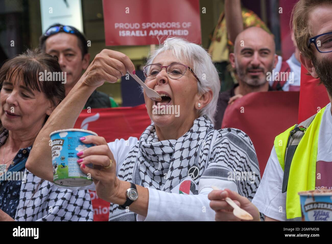 London, UK. 18 Sept 2021. A woman outside the London Puma store in Carnaby Street celebrates the decision by Ben & Jerry to boycott Israel by eating their ice cream in the protest on the #BoycottPUMA Global Day of Action. They call on Puma to end its sponsorship of the Israel Football Association, which governs teams in illegal Israeli settlements in the occupied Palestinian West Bank. A small group with Israeli flags came to support Puma. Peter Marshall/Alamy Live News Stock Photo