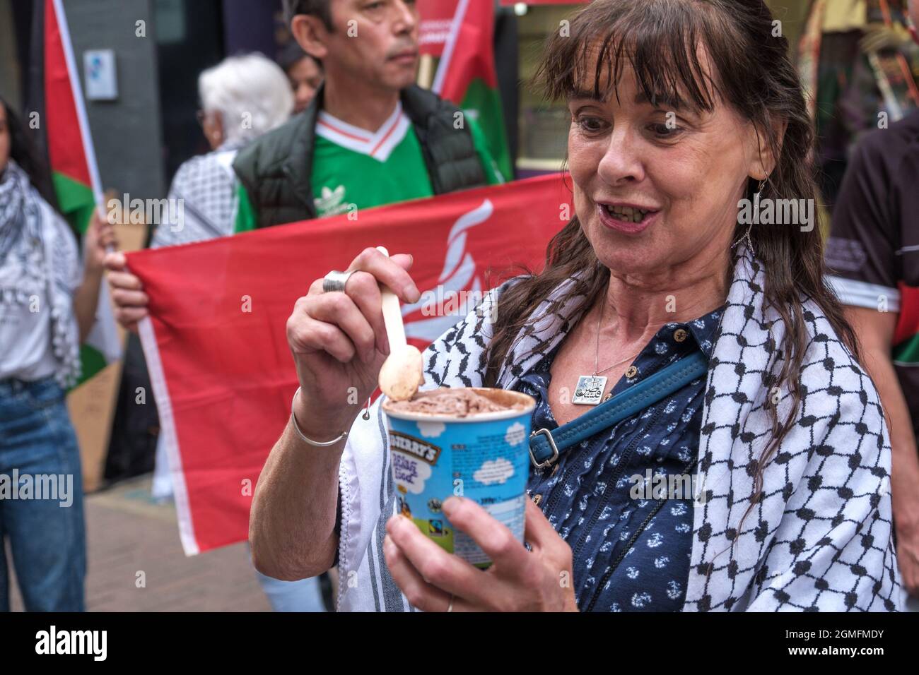 London, UK. 18 Sept 2021. A woman outside the London Puma store in Carnaby Street celebrates the decision by Ben & Jerry to boycott Israel by eating their ice cream in the protest on the #BoycottPUMA Global Day of Action. They call on Puma to end its sponsorship of the Israel Football Association, which governs teams in illegal Israeli settlements in the occupied Palestinian West Bank. A small group with Israeli flags came to support Puma. Peter Marshall/Alamy Live News Stock Photo