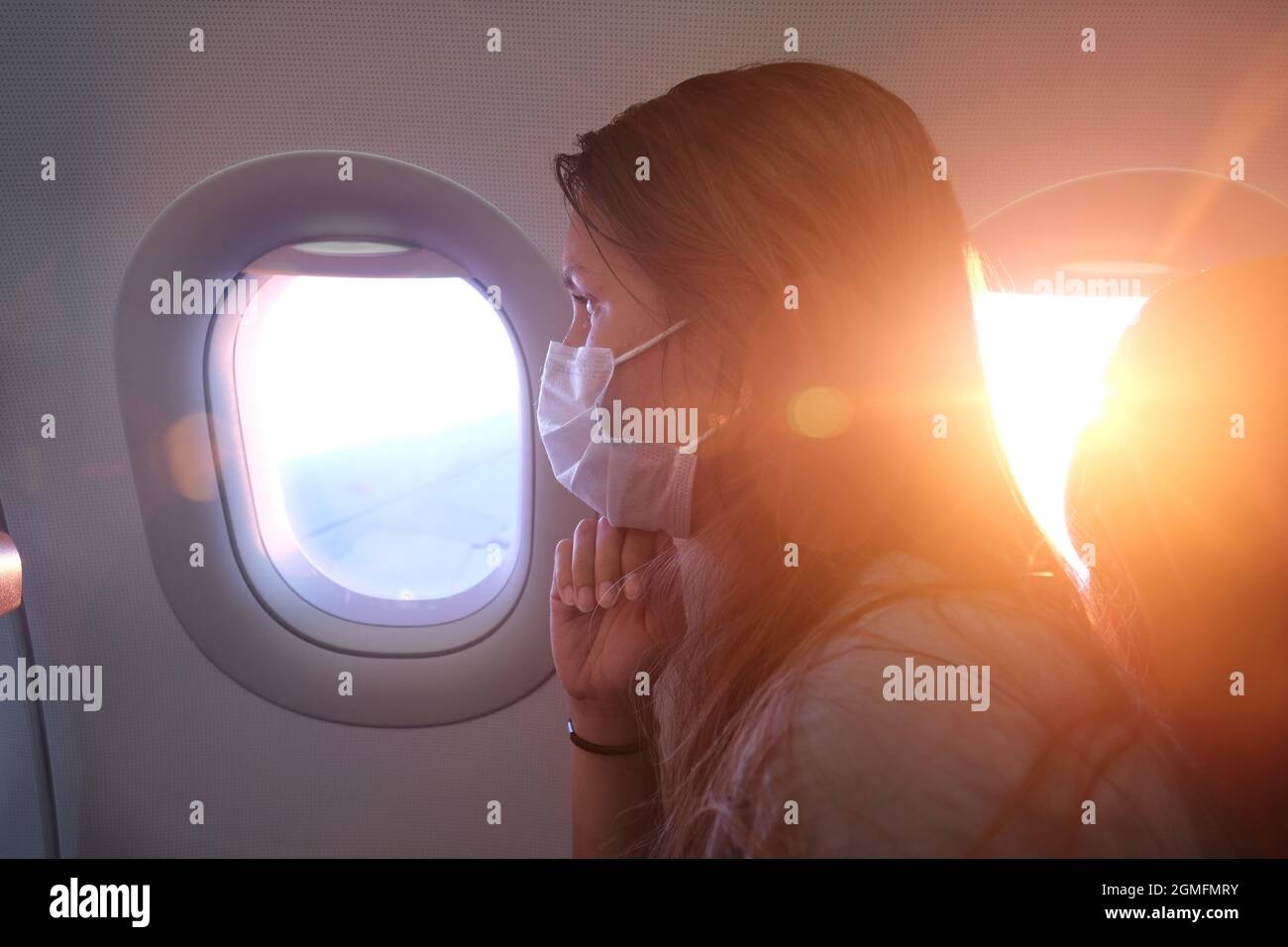 Woman in a Face Mask in Airplane During the COVID19 Pandemic Stock