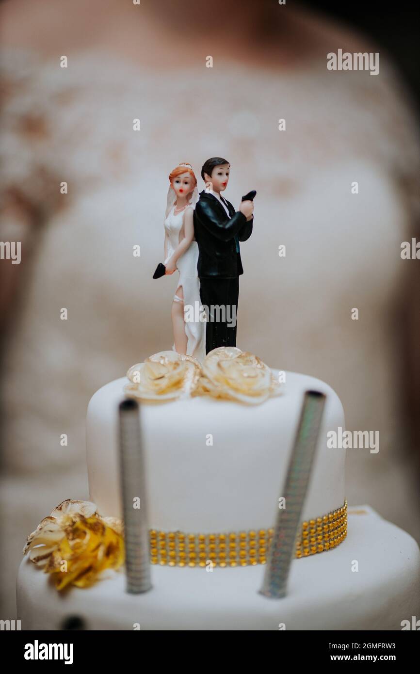 Vertical shot of a wedding decorated cake with bride and groom marzipan ...