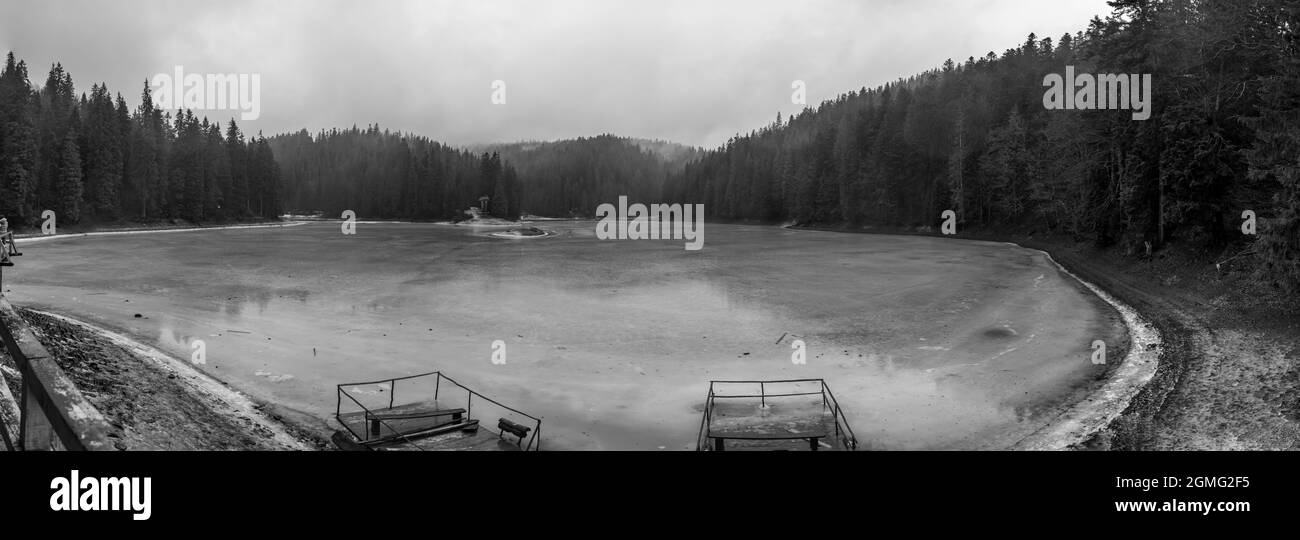 A panoramic winter view of a high mountain lake Synevir located in the Carpathian Mountains, Ukraine. Black and white shot. Stock Photo