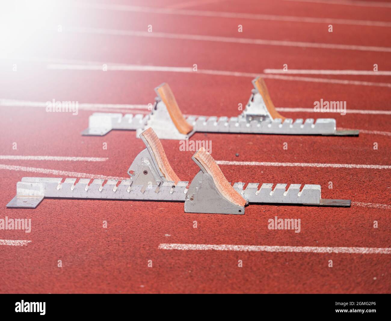 Starting blocks on red running tracks, light reflection an lens flare