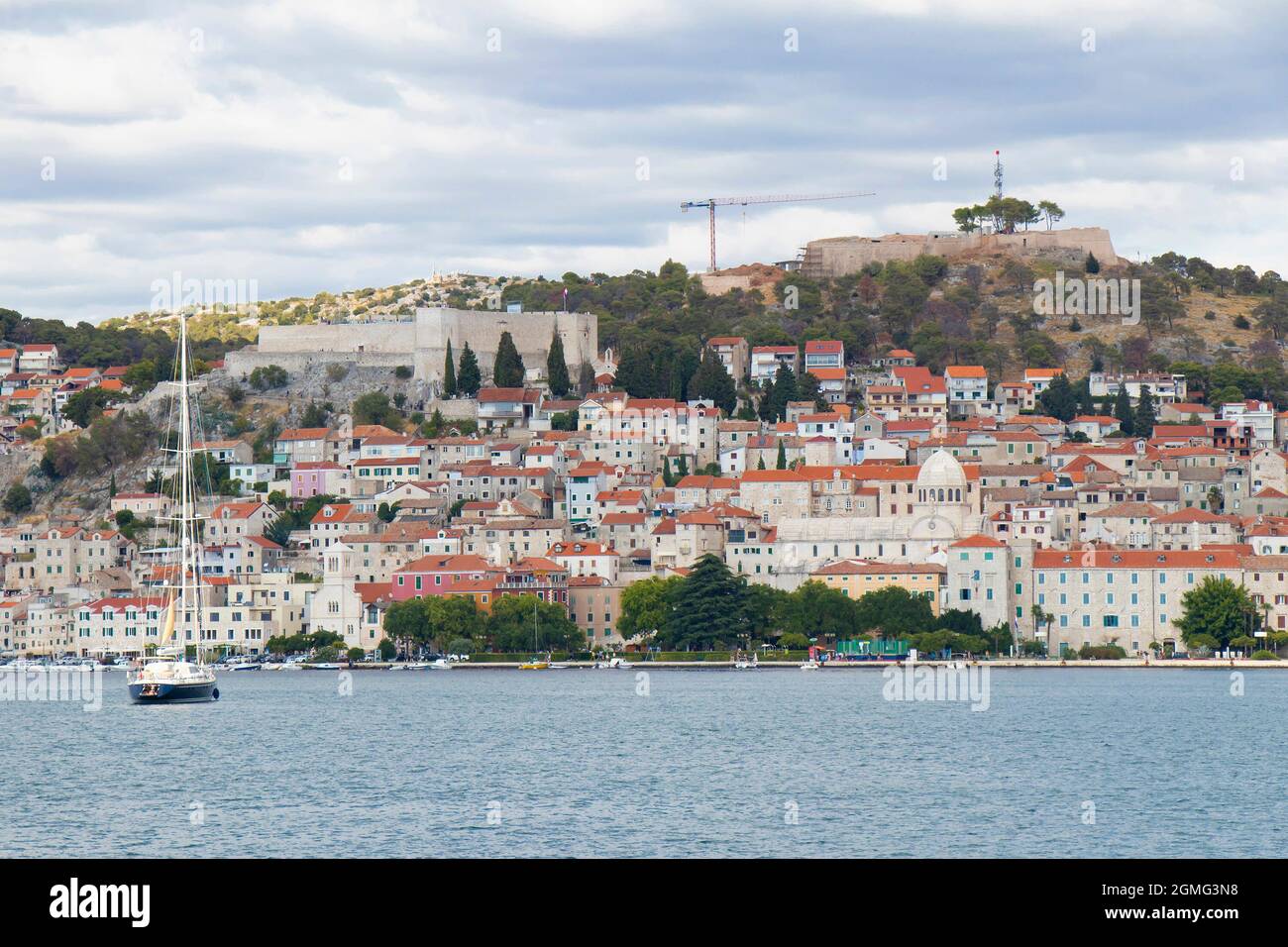 Sibenik, Croatia - August 25, 2021: Old own with harbor, promenade, stone houses, cathedral and fortress viewed from the sea when arriving by ship Stock Photo