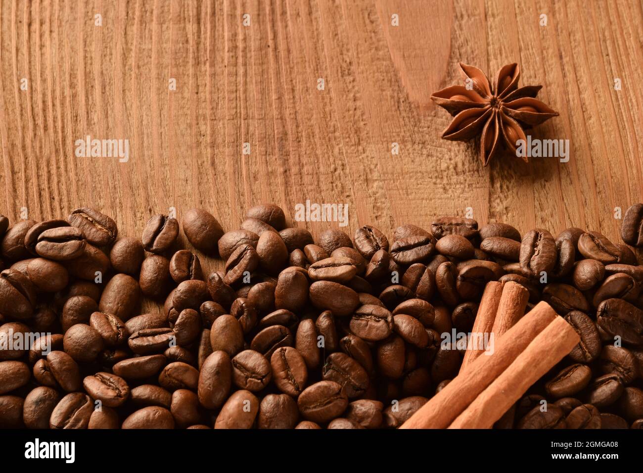 Sprinkled coffee beans at the bottom of the photo, as well as anise and cinnamon. Above photo of empty brown wooden background Stock Photo