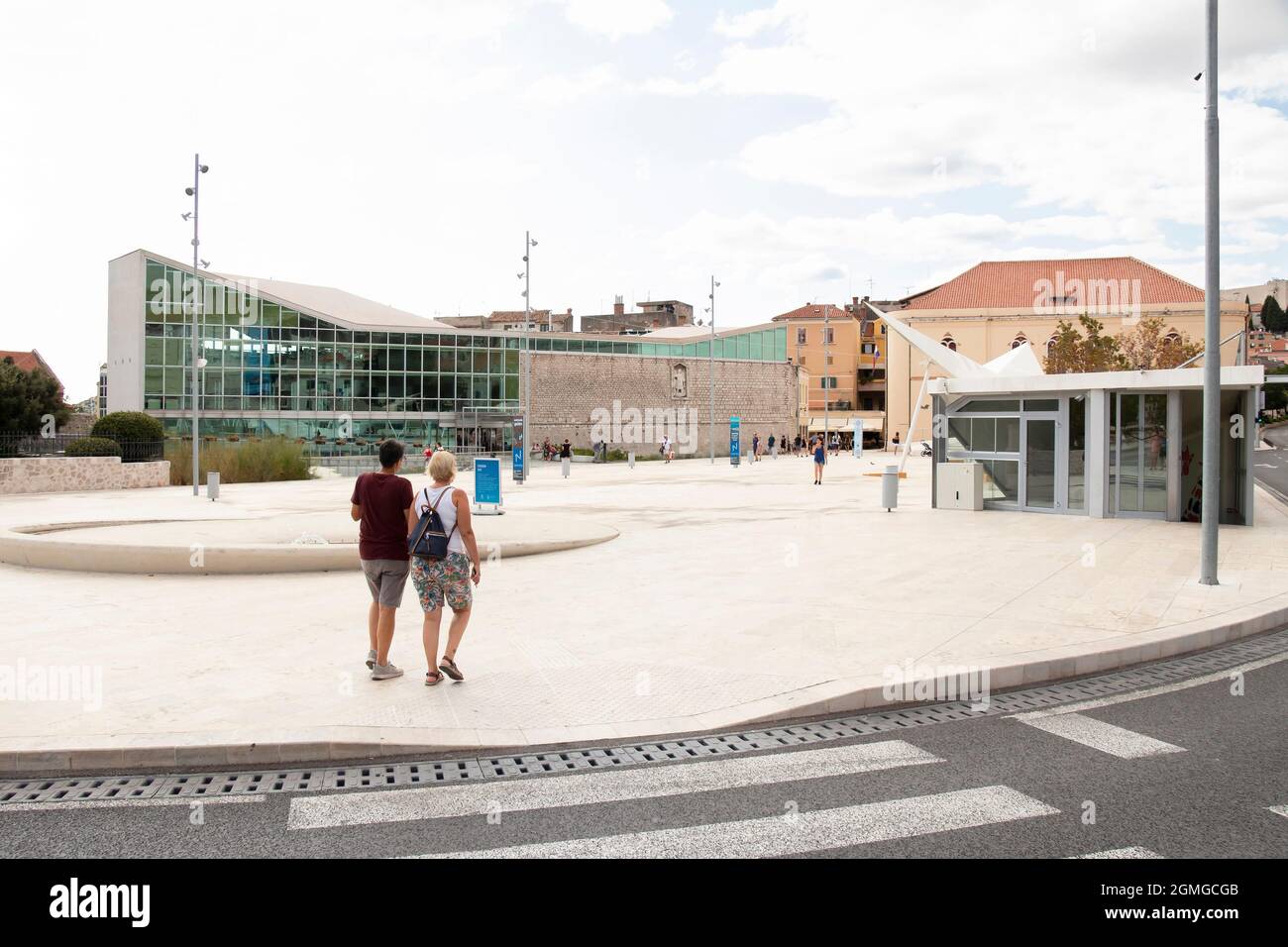 Sibenik, Croatia - August 25, 2021: City square in front of old town, with stone and glass public library building and underground garage entrance Stock Photo