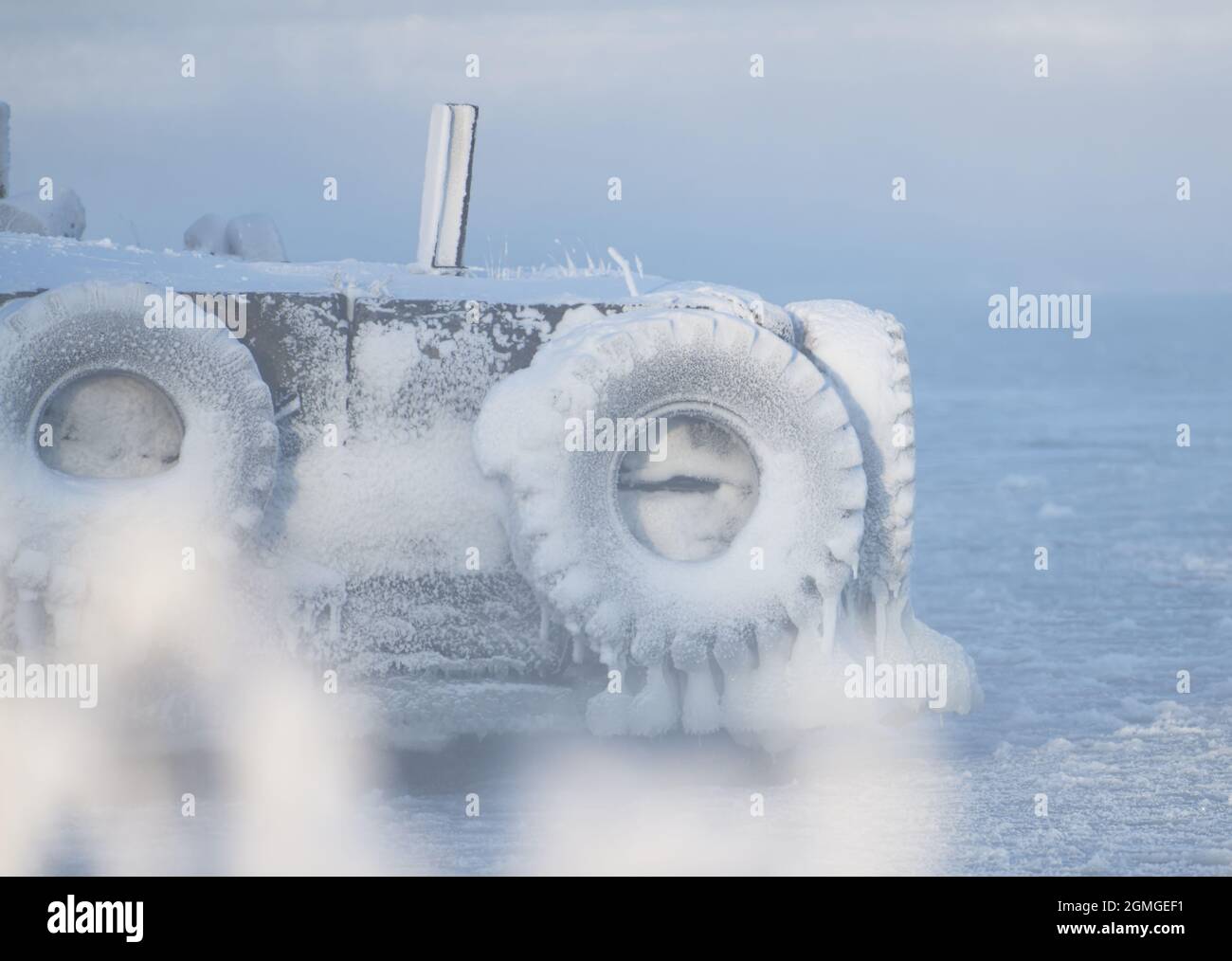 Ice covered boat docks with tractor wheels by the Baltic sea in Helsinki, Finland. Stock Photo
