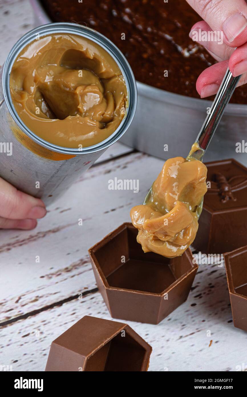 Confectioner putting dulce de leche in small chocolate molds to make Brazilian honey cake. Stock Photo