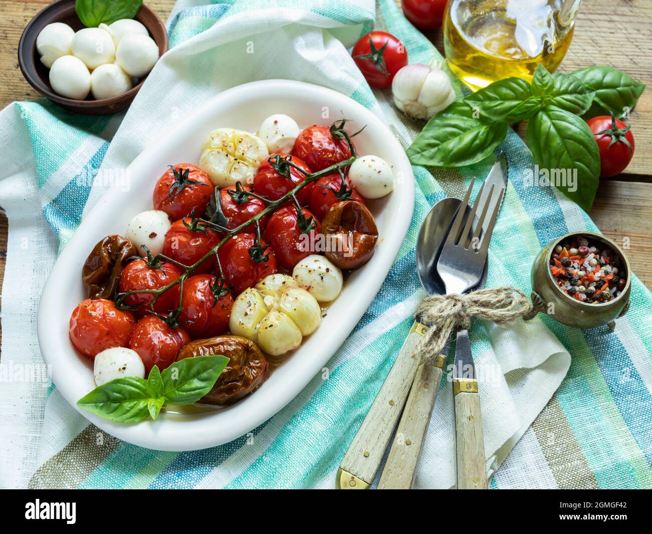 Salad. Baked tomato, basil, garlic with mozzarella cheese in ceramic dishes. cooking, cooked vegetarian dish Stock Photo