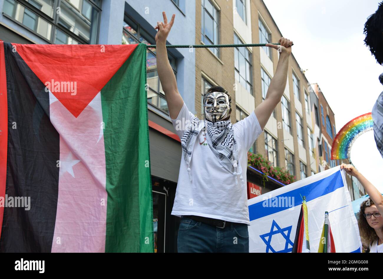 A protestor wearing a Guy Fawkes mask holding a Palestinian flag, during the demonstration. Boycott Puma protest organized by Palestine Solidarity Campaign and FOA (Friends of Al Aqsa) at Puma flagship store on Carnaby Street, London. Stock Photo
