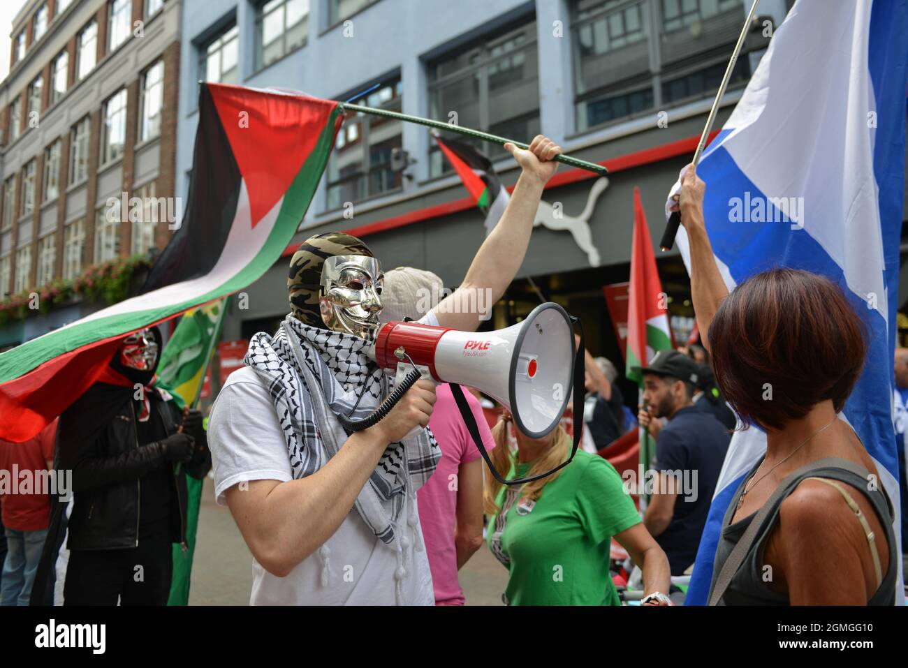An activist with a megaphone confronts a counter protester with an Israeli flag during the demonstration. Boycott Puma protest organised by Palestine Solidarity Campaign and FOA (Friends of Al Aqsa) at Puma flagship store on Carnaby Street, London. Stock Photo