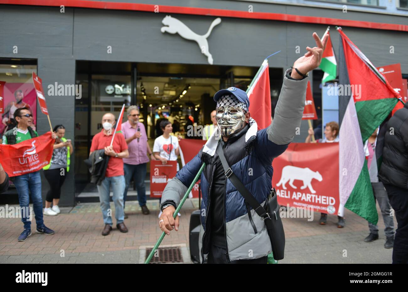 A protestor wearing a Guy Fawkes mask holding a Palestinian flag, during the demonstration. Boycott Puma protest organized by Palestine Solidarity Campaign and FOA (Friends of Al Aqsa) at Puma flagship store on Carnaby Street, London. Stock Photo