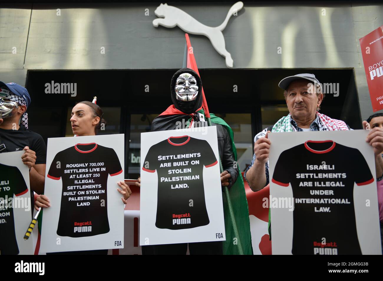 Protesters with banners are taking part in Boycott Puma protest at front of Puma flagship store on Carnaby Street, London. Stock Photo