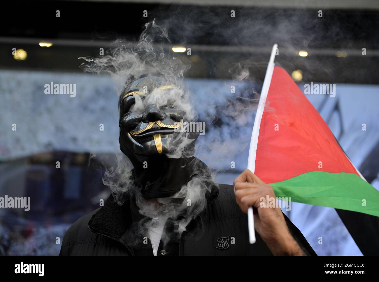 A protestor wearing a Guy Fawkes holding a Palestinian flag, smoking, during the demonstration.Boycott Puma protest organised by Palestine Solidarity Campaign and FOA (Friends of Al Aqsa) at Puma flagship store on Carnaby Street, London. Activists demonstrated against Puma's sponsorship of the IFA (Israel Football Association). (Photo by Thomas Krych / SOPA Images/Sipa USA) Stock Photo