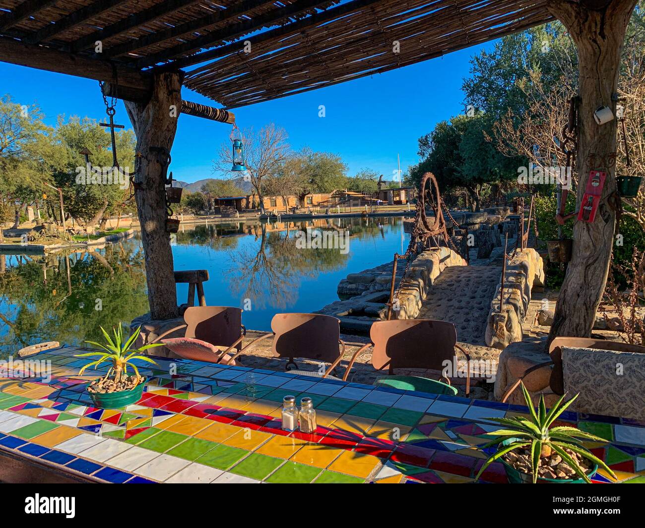 Garden dining table decorated with colored tiles, plants under wooden roof  outdoors in the garden with pool in the town of Ures, Sonora, Mexico. real  state, Hacienda Labrador, history, ranches and haciendas