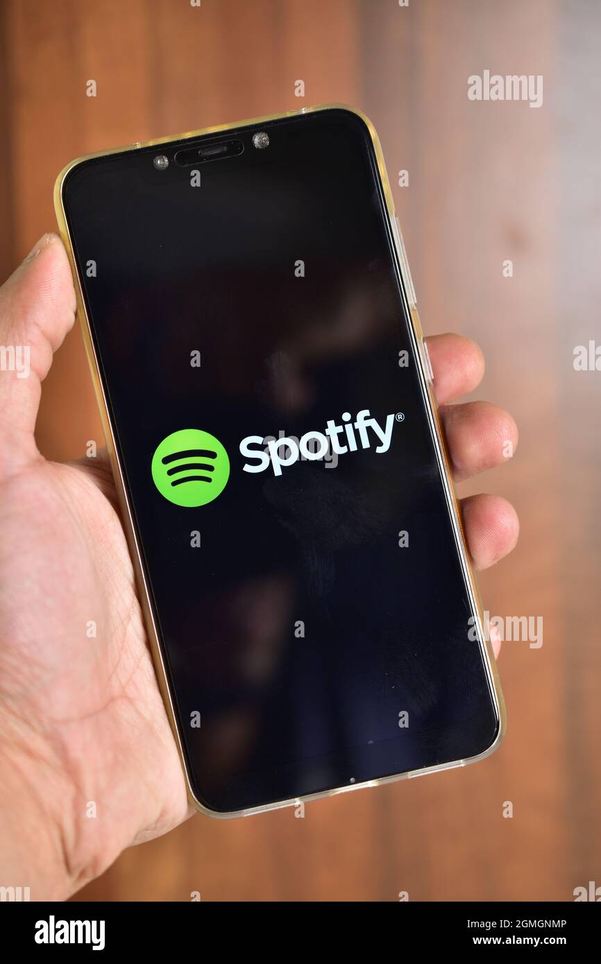 Delhi, India, October 23, 2019: Close up of hand  holding Smartphone and using Spotify application on the screen. Spotify is a music streaming platform Stock Photo