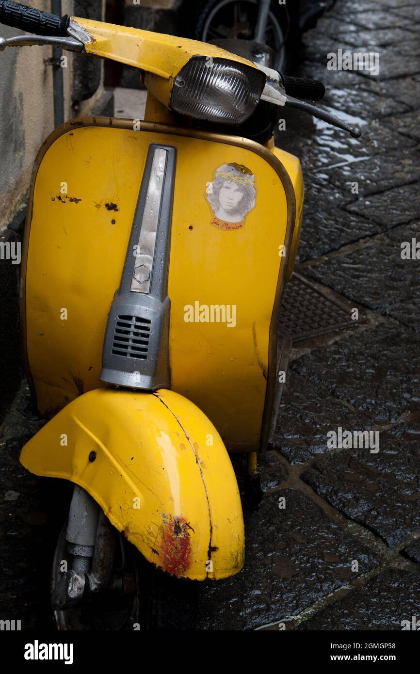 A retro yellow Vespa scooter sits idly on the rain-damped streets of  Ravello, Italy. Stock Photo