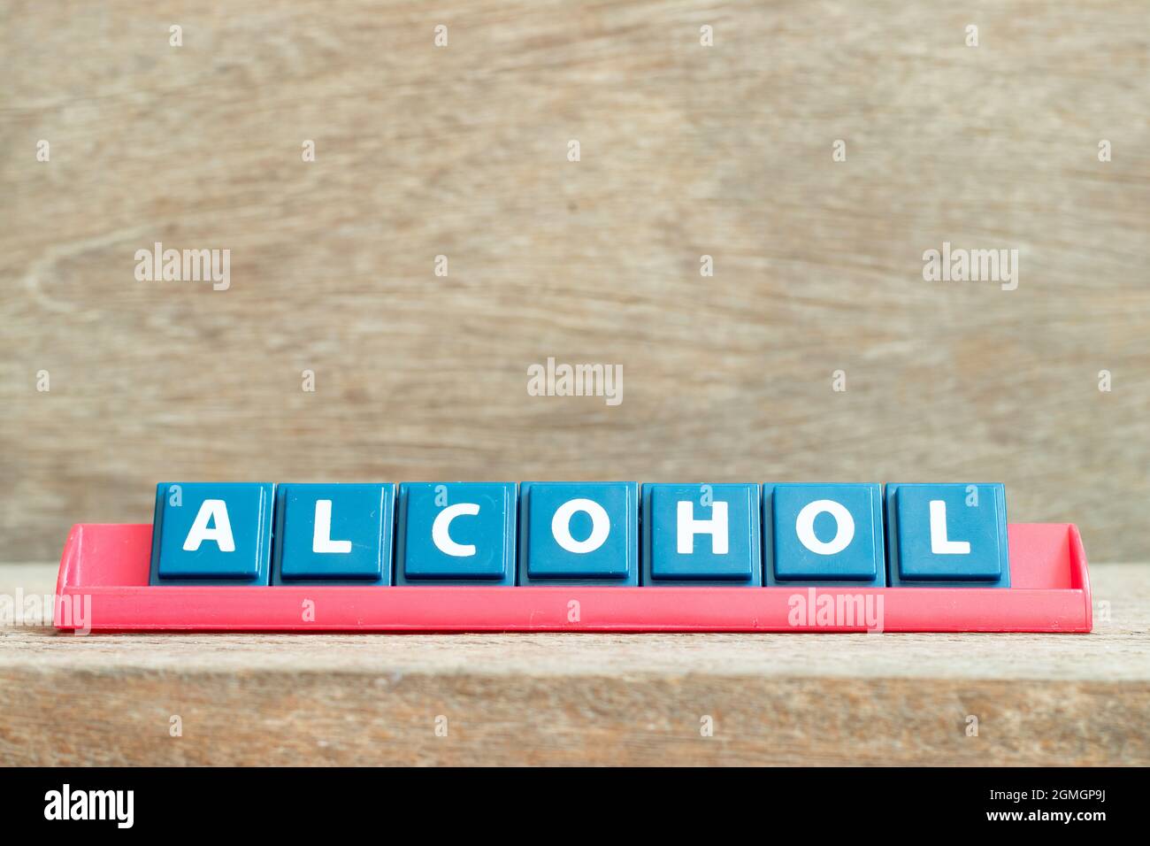 Tile alphabet letter with word alcohol in red color rack on wood