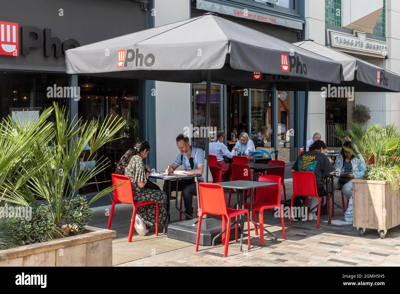 People sitting at outside tables and dining al fresco at a Pho restaurant, eating Vietnamese street food, UK Stock Photo