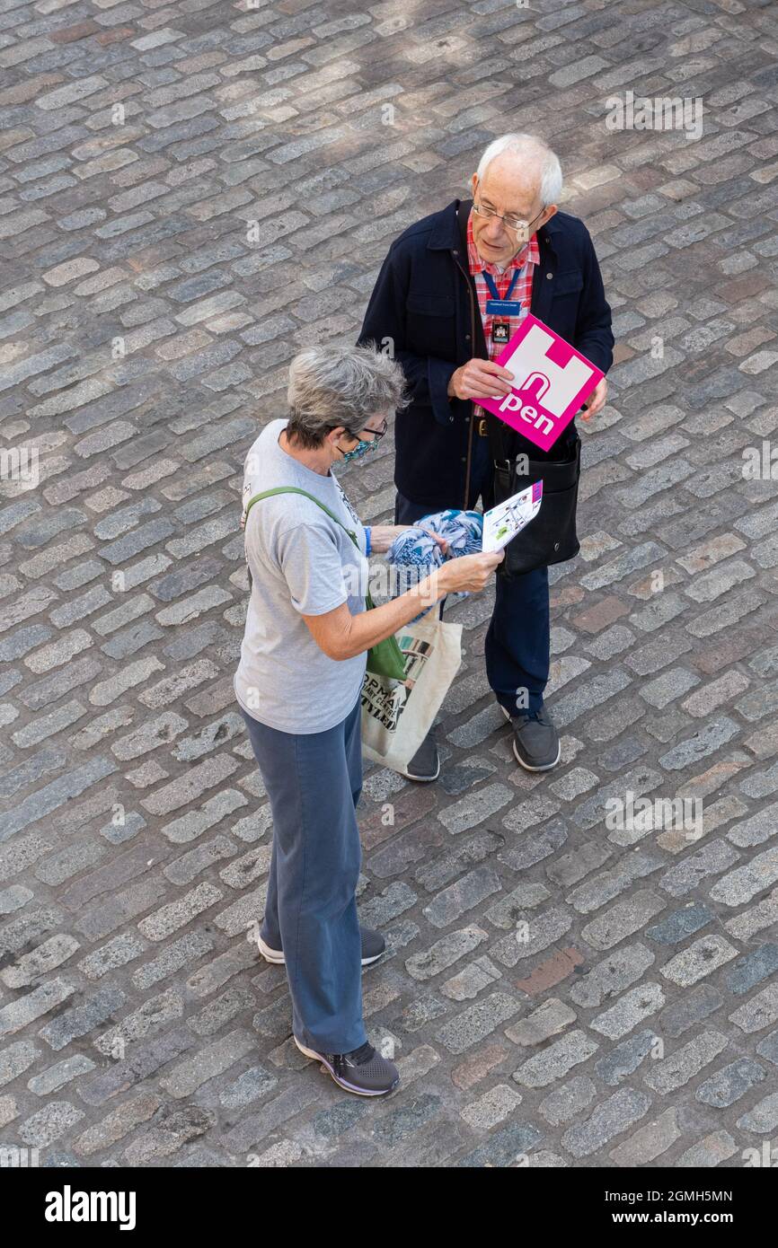 Man telling a woman about the English Heritage Open Day event in Guildford town centre, UK, during September Stock Photo