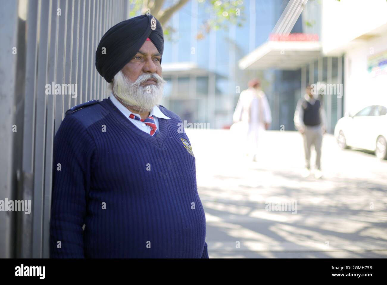 Old Sikh Security guard in blue dress on duty in alert position Stock Photo