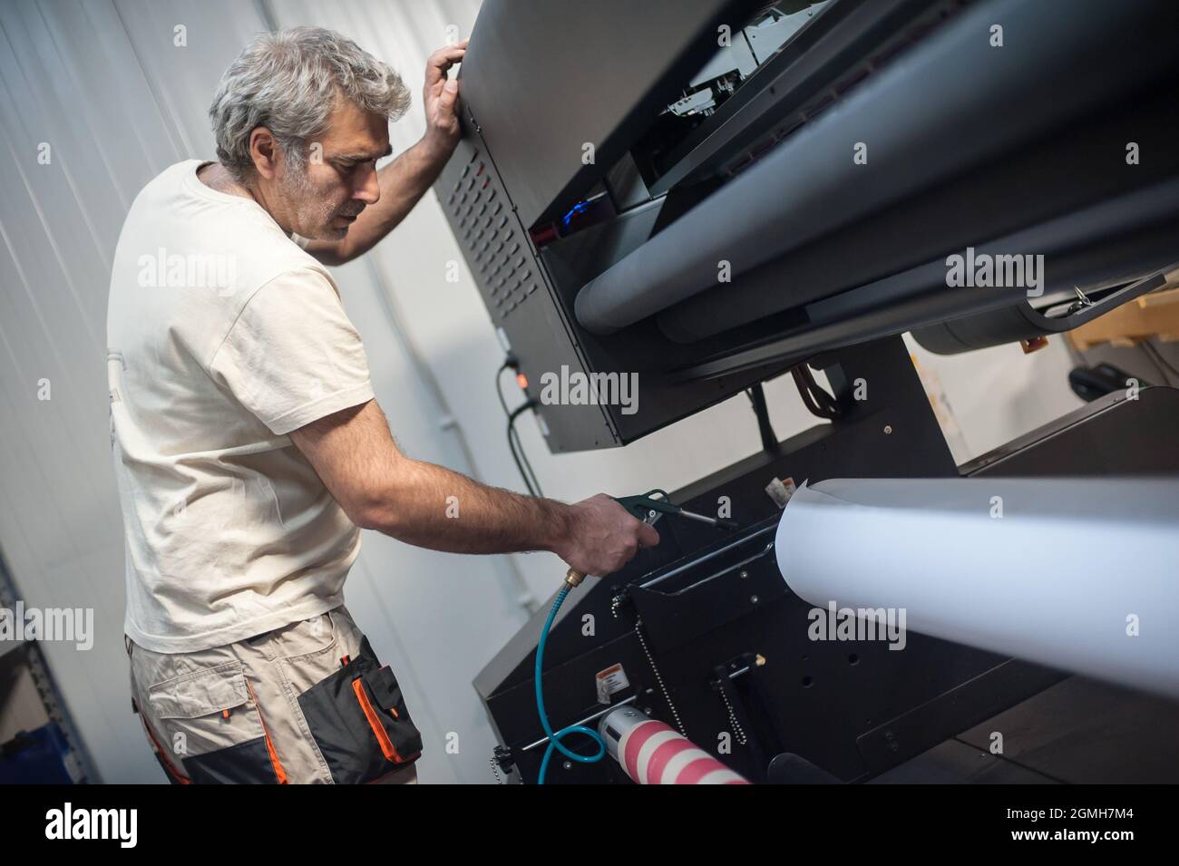 Technician worker operator works on large premium industrial printer